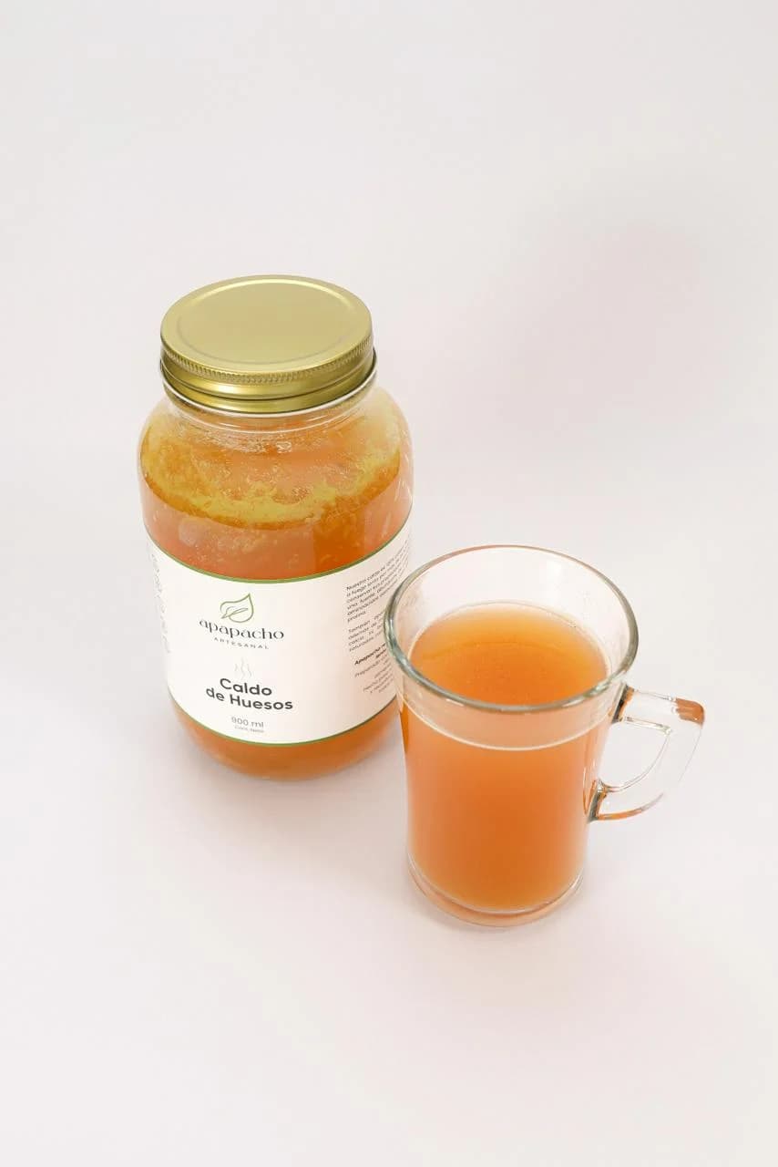 Caldo de Hueso Apapacho servido con taza y cuchara de madera